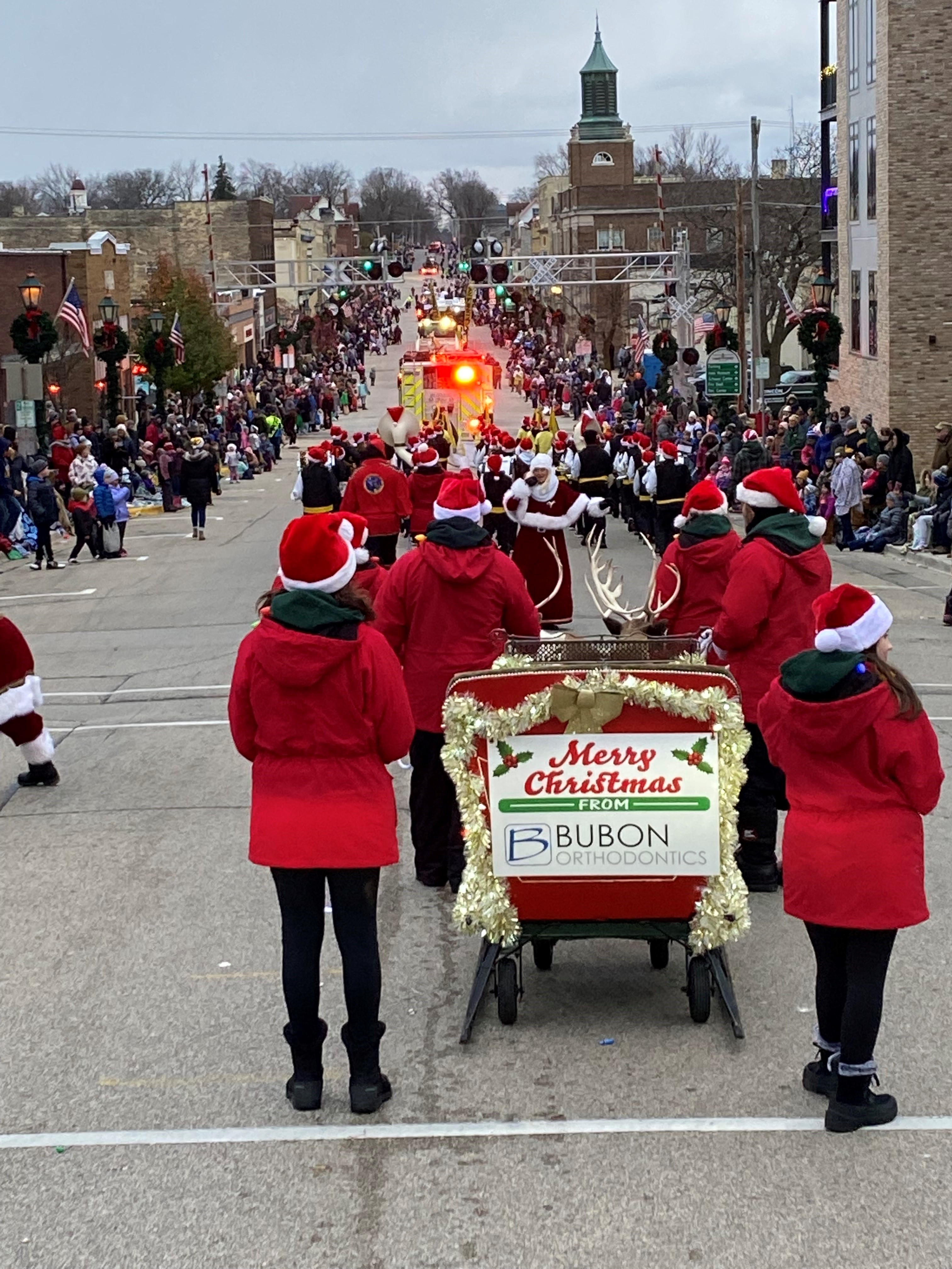 A festive Christmas parade with participants in red Santa hats
